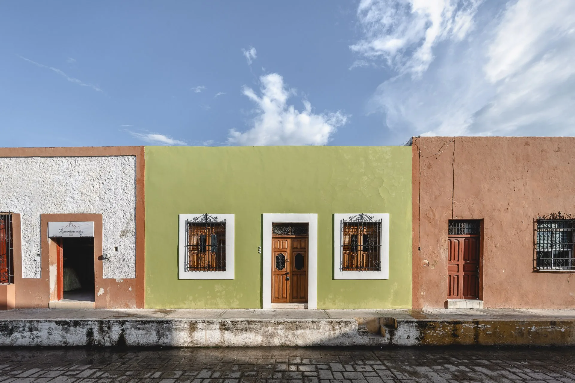 Fachada verde con marcos blancos de La Casa Verde entre sus vecinas, en la ciudad amurallada de Campeche