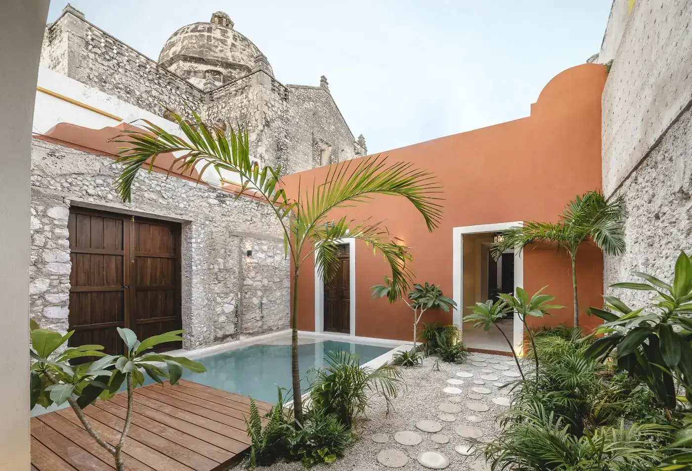Patio restaurado de Casa Ex Templo con alberca de chukum y la cúpula del ex templo de San José, Campeche. Casonas MX
