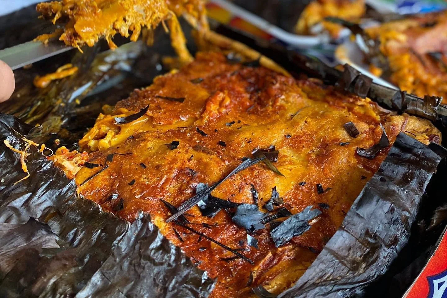 Pibipollo recién abierto en su hoja de plátano, con una porción servida