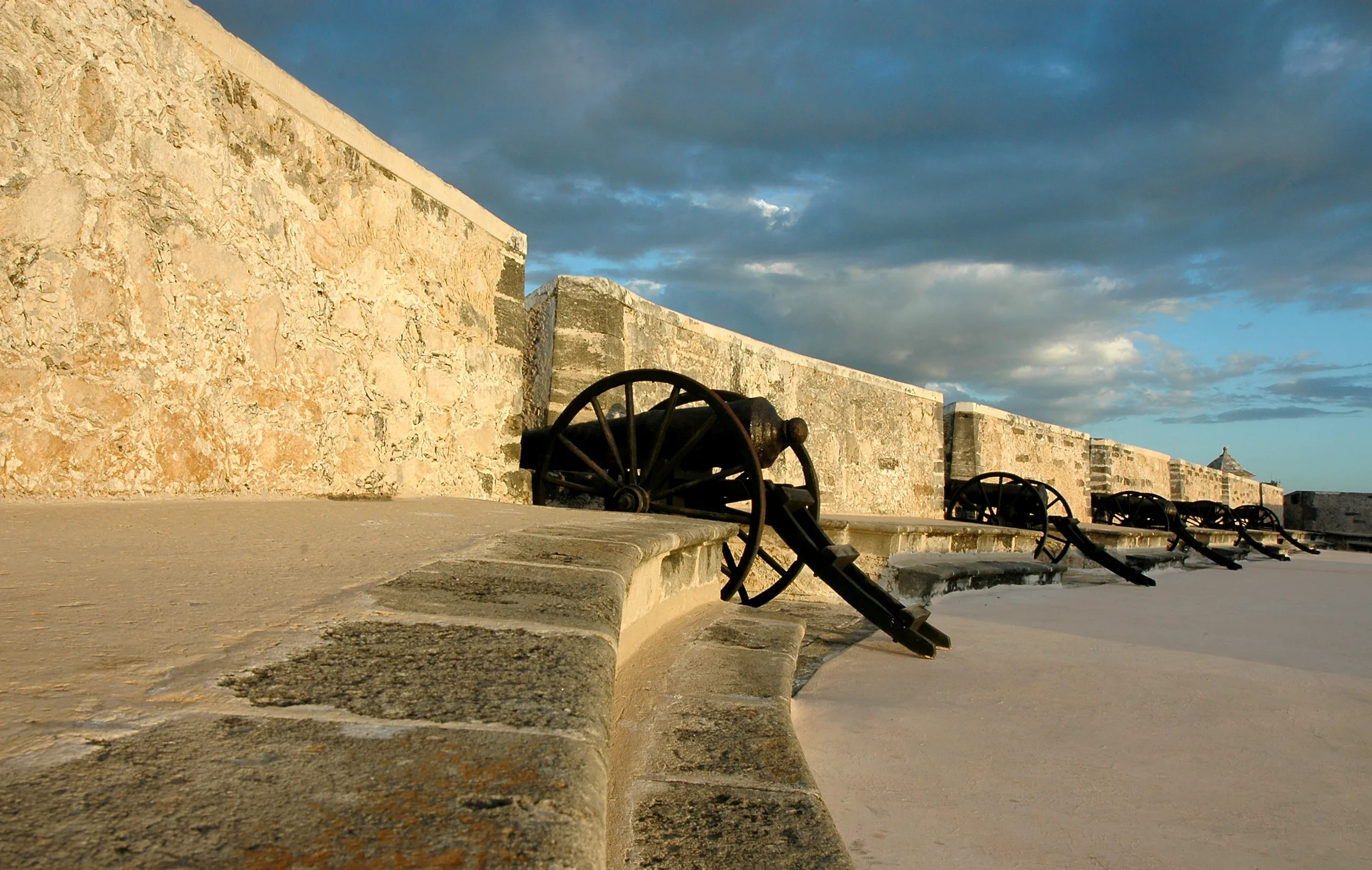 Cañones sobre el parapeto de piedra del Fuerte de San Miguel, en Campeche, bajo un cielo con nubes