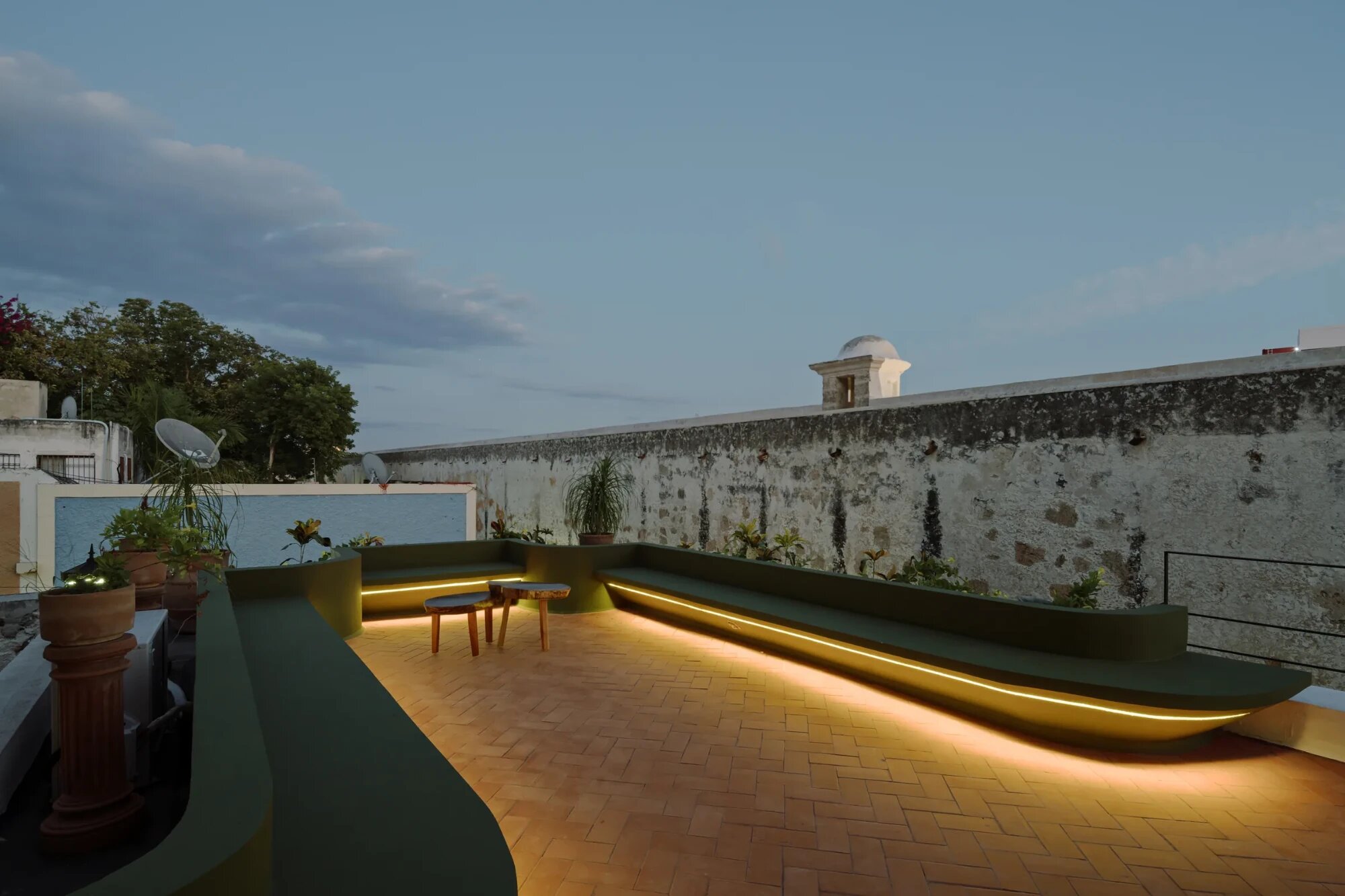 Azotea de Casa Muralla frente a la muralla de Campeche, con bancas iluminadas al anochecer