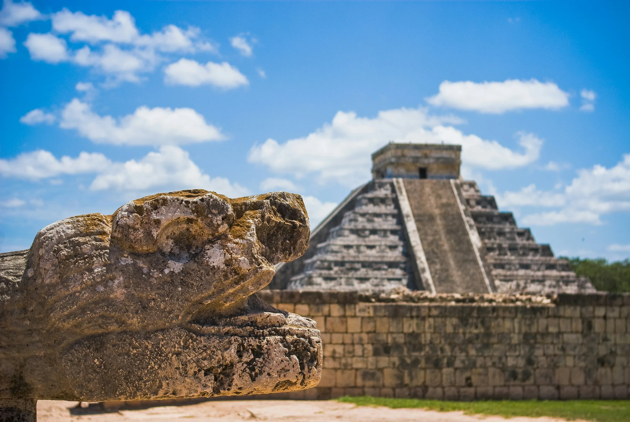 El Castillo de Chichén Itzá tras una cabeza de serpiente labrada en piedra. Casonas MX